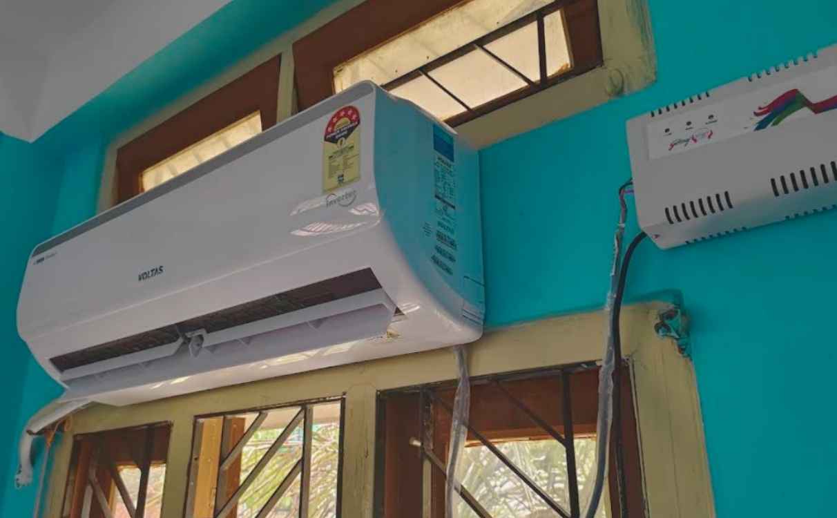 Wall-mounted Voltas 125V Vectra Elite 1 Ton 5 Star inverter AC indoor unit installed with stabilizer and connected wiring and copper pipe lines